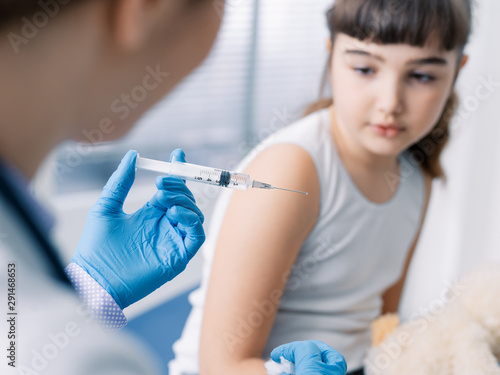 Female doctor giving an injection to a young cute girl