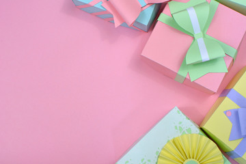 Flat lay background with pastel colored paper craft gift boxes with ribbons right side and copy space of pink background