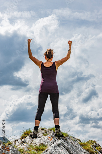 Weibliche Silhouette in Siegerpose auf einem Berggipfel