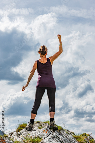 Weibliche Silhouette in Siegerpose auf einem Berggipfel