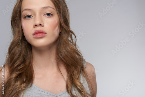 Beautiful teen girl with long brown hair posing against gray-white background