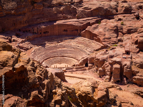 View of the valley of the historic site of Petra, Jordan, orange desert full of temples and a roman amphitheatre, seen from aerial perspective from a sandstone mountain