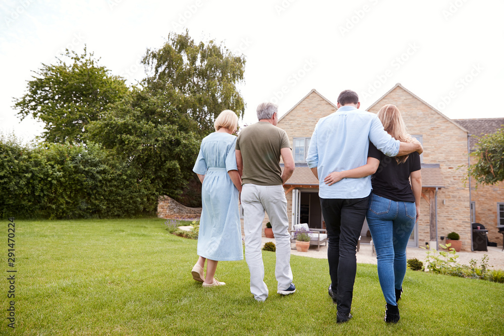 Rear View Of Family With Senior Parents And Adult Offspring Walking And Talking In Garden Together Rear View Of Family With Senior Parents And Adult Offspring Walking And Talking In Garden Together