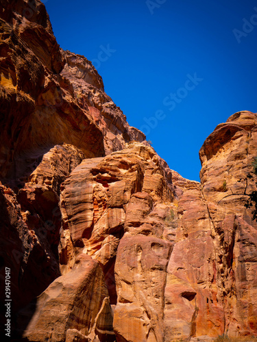 Orange walls of a canyon in the historic sight of Petra, Jordan, in the mountains of the desert under blue sky © duqimages