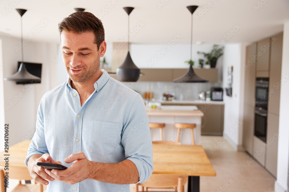 Man Using App On Smart Phone To Control Central Heating Temperature In House Man Using App On Smart Phone To Control Central Heating Temperature In House