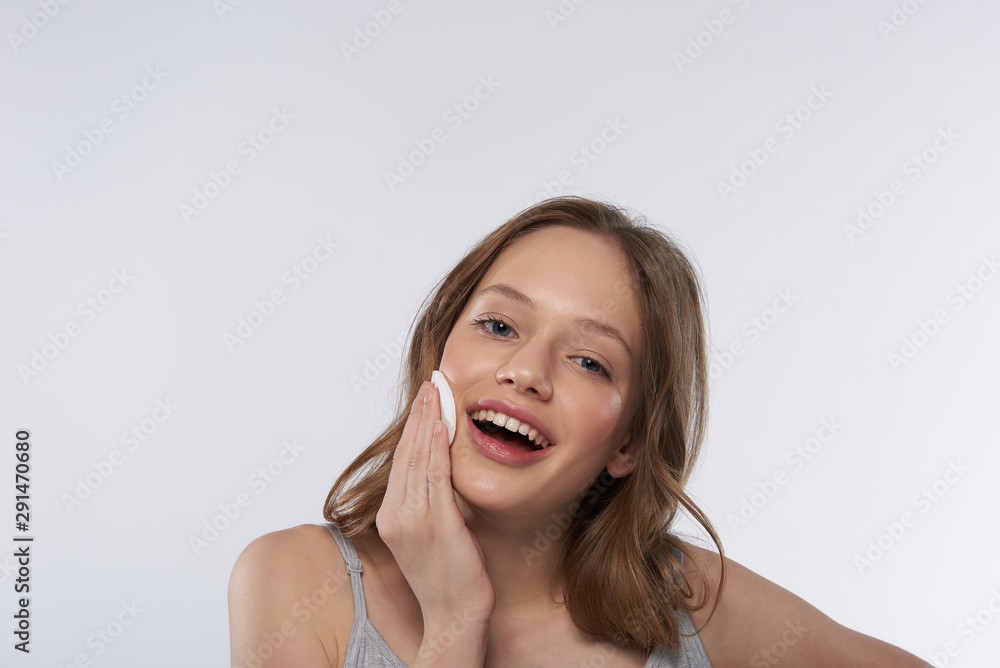 Charming teen girl using cotton pad and smiling Charming teen girl using cotton pad and smiling