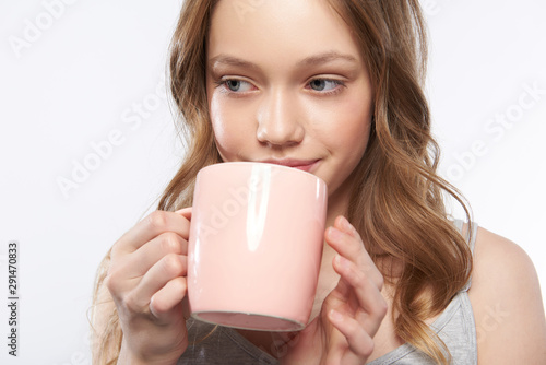 Beautiful teen girl with curly brown hair drinking coffee