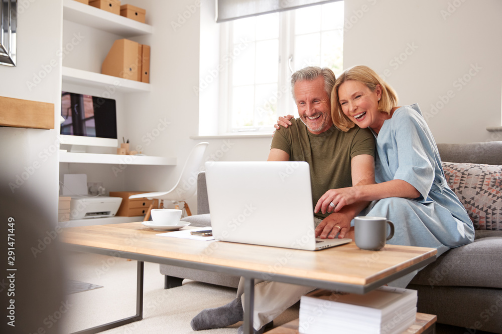 Senior Couple Sitting On Sofa In Lounge At Home Using Laptop Together Senior Couple Sitting On Sofa In Lounge At Home Using Laptop Together