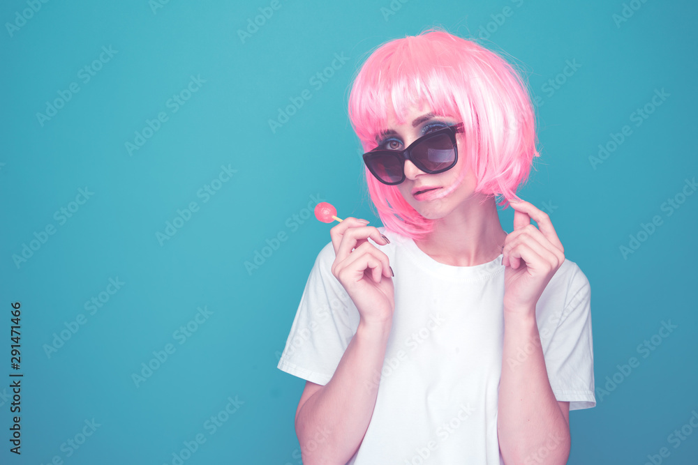Bautiful 90s girl in a whit t-shurt and black glasses with lollipop in a blue room Bautiful 90s girl in a whit t-shurt and black glasses with lollipop in a blue room