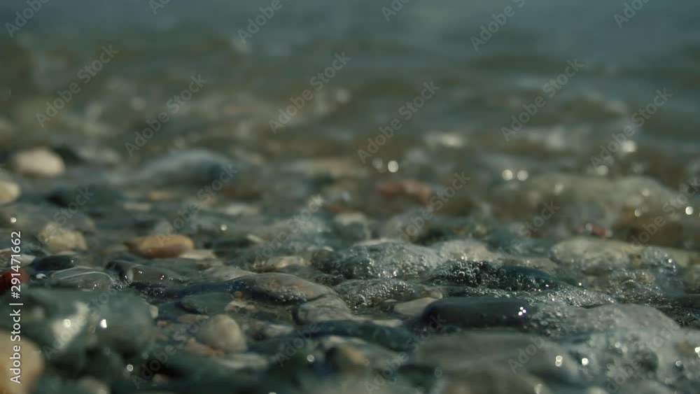 Wave Splashing Over Pebbles At Sea.Close Up Sea Ocean Beach In Slow Motion.Waves Crashing In Background And Wave Splashing Over Pebbles.Close-Up Air Buble On Pebbles.Vocation Or Summer Holiday Concept Wave Splashing Over Pebbles At Sea.Close Up Sea Ocean Beach In Slow Motion.Waves Crashing In Background And Wave Splashing Over Pebbles.Close-Up Air Buble On Pebbles.Vocation Or Summer Holiday Concept
