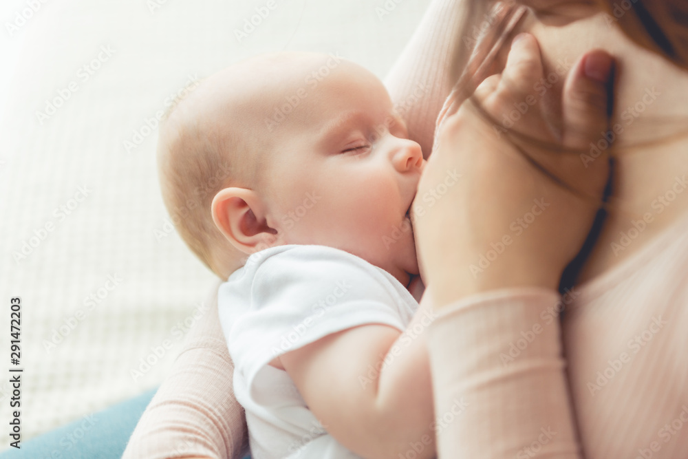 cropped view of mother breastfeeding her child in apartment - obrazy, fototapety, plakaty 