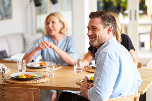 Family With Senior Mother And Adult Offspring Eating Brunch Around Table At Home Together
