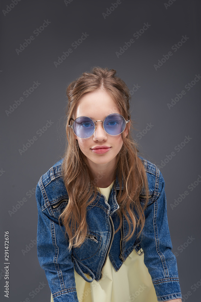 Cute teen girl in denim jacket standing against blue-gray background Cute teen girl in denim jacket standing against blue-gray background