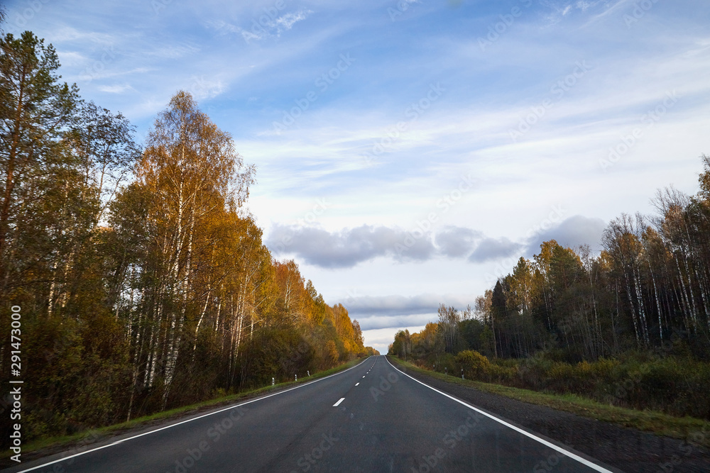 Track from the car window and white clouds on blue sky. Natural landscape