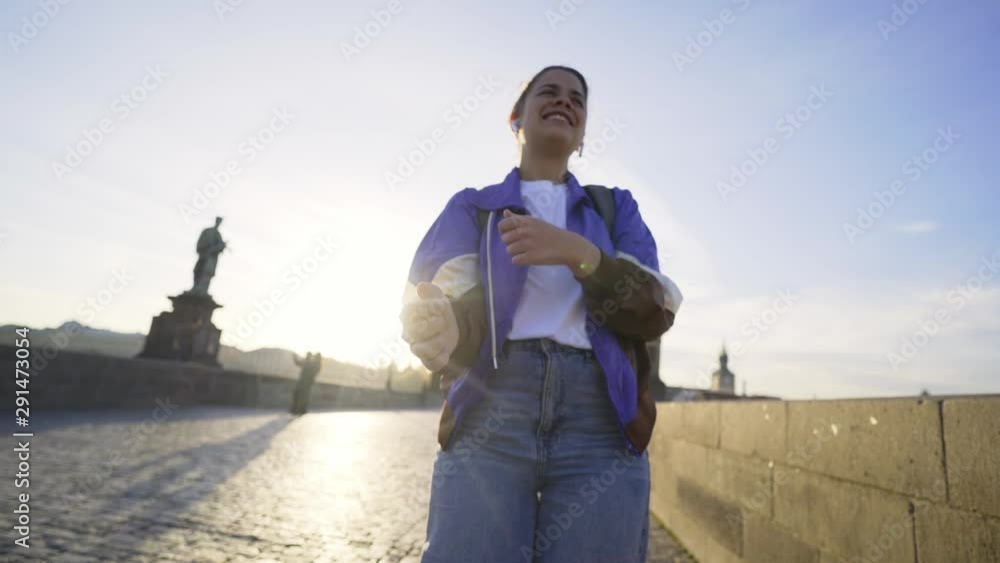 Female walking in historical centre of Prague at morning time. Wide shot woman 80's style clothes. Joyfuly girl have fun, dancing extravagantly, grimacing and singing on camera in backlit Female walking in historical centre of Prague at morning time. Wide shot woman 80's style clothes. Joyfuly girl have fun, dancing extravagantly, grimacing and singing on camera in backlit