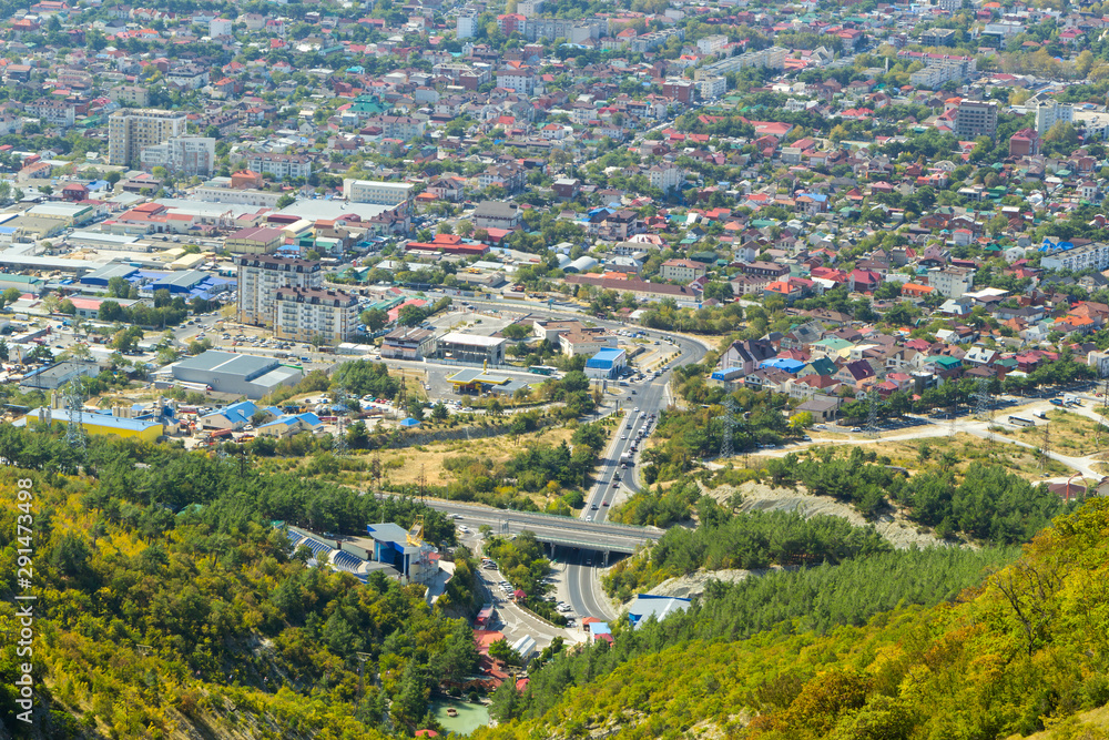Aerial view of Gelendzhik resort city district from hill of caucasian mountains. Buildings and street at the foot of the mountains.