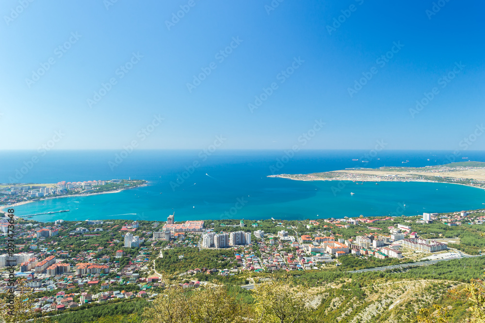 Aerial view of Gelendzhik sea bay. Buildings, beaches, ships in blue water of Black sea bay and horizon in frame.
