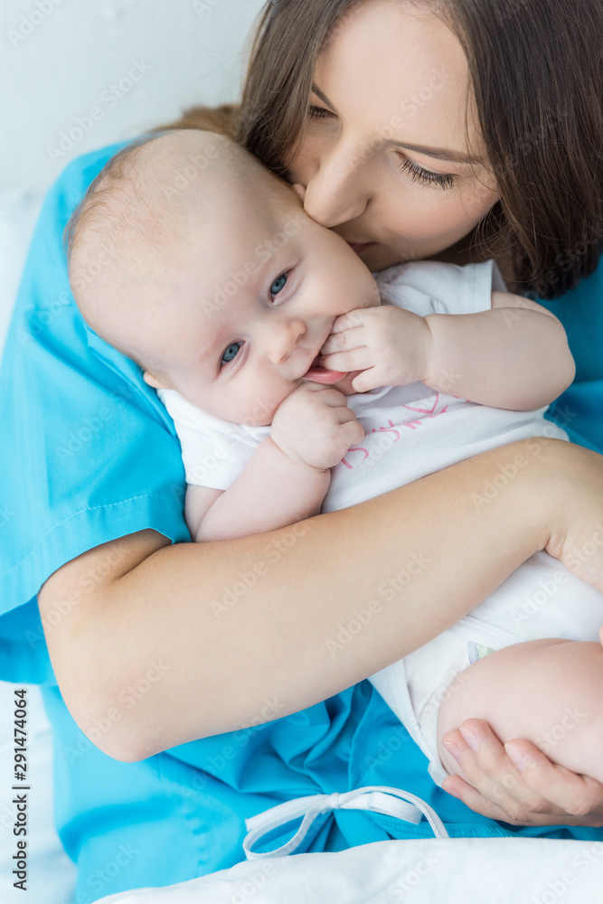attractive and young mother holding and kissing her child in hospital attractive and young mother holding and kissing her child in hospital