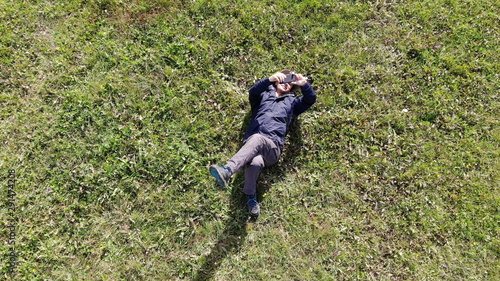 man laying on the grass and making selfie aerial shot