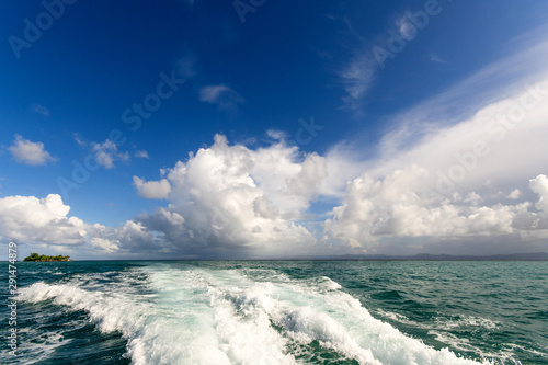 Fototapeta Naklejka Na Ścianę i Meble -  Wide angle shot on the open sea with blue and tourquoise oceans's surface with waves and blue sky with cloudsduring a boat trip around the wonderful island Samana, Dominican Republic in the Caribbean.