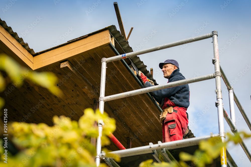 worker on scaffolding renovating wooden roof structure worker on scaffolding renovating wooden roof structure