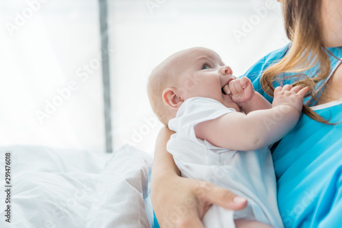 cropped view of mother holding her child in hospital