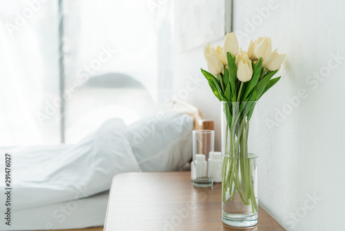 selective focus of tulips in vase, glass and bottles on wooden table in clinic