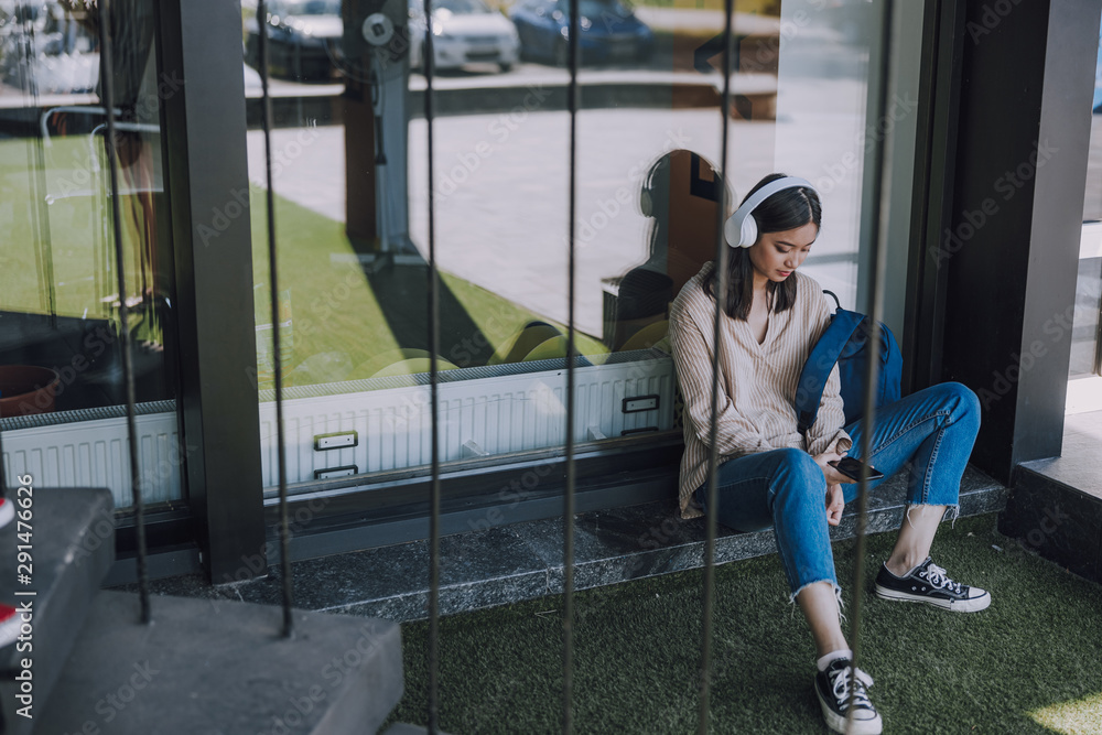 Happy Asian lady in headphones posing for camera indoors