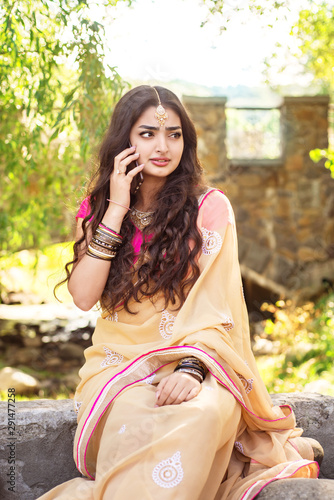 Indian girl sitting in park and talking to mibile phone