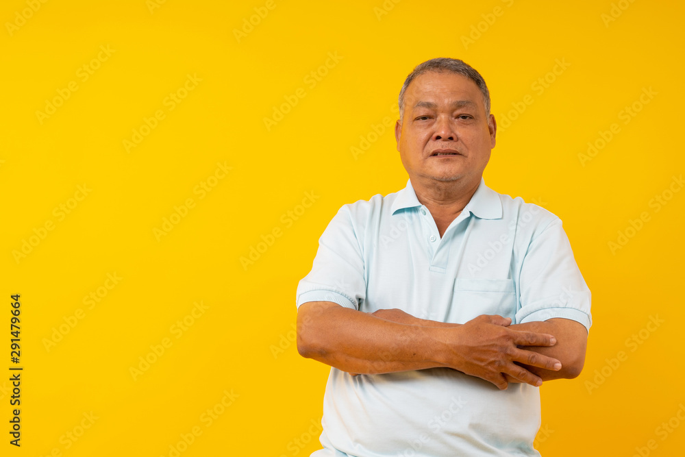 confident old Thai man fold arm and look at camer on yellow background in studio confident old Thai man fold arm and look at camer on yellow background in studio