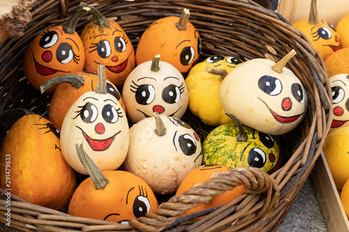 A full basket of decorative pumpkins with painted funny faces fo