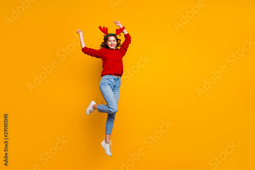 Full length photo of cheerful lady jumping high xmas party wear knitted pullover isolated yellow background