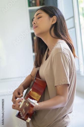 woman playing, practicing guitar; concept of music, hobby, relaxation