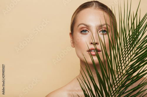 Blonde woman posing naked with green nature leaf plant.