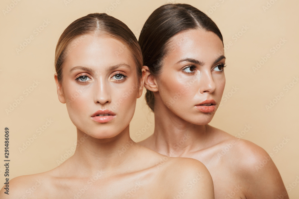 Women posing naked isolated over beige wall background. Women posing naked isolated over beige wall background.