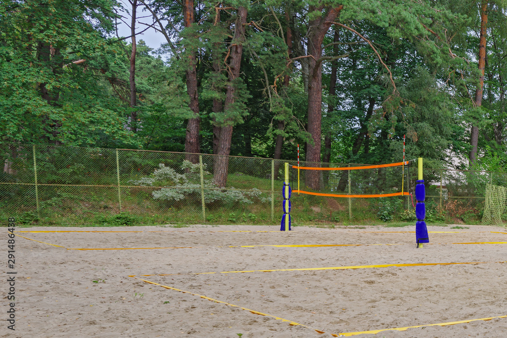 The empty beach volleyball courts in a residential neighborhood surrounded by green trees