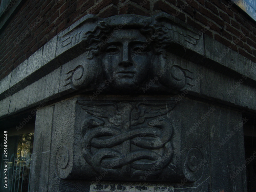 Stone head on corner of building with snake symbol