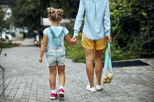 Woman with shopping bag walking with girl stock photo