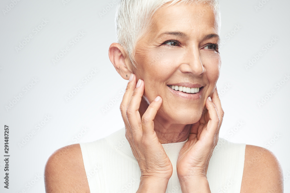Beautiful smiling senior woman with short gray hair posing in front of ...