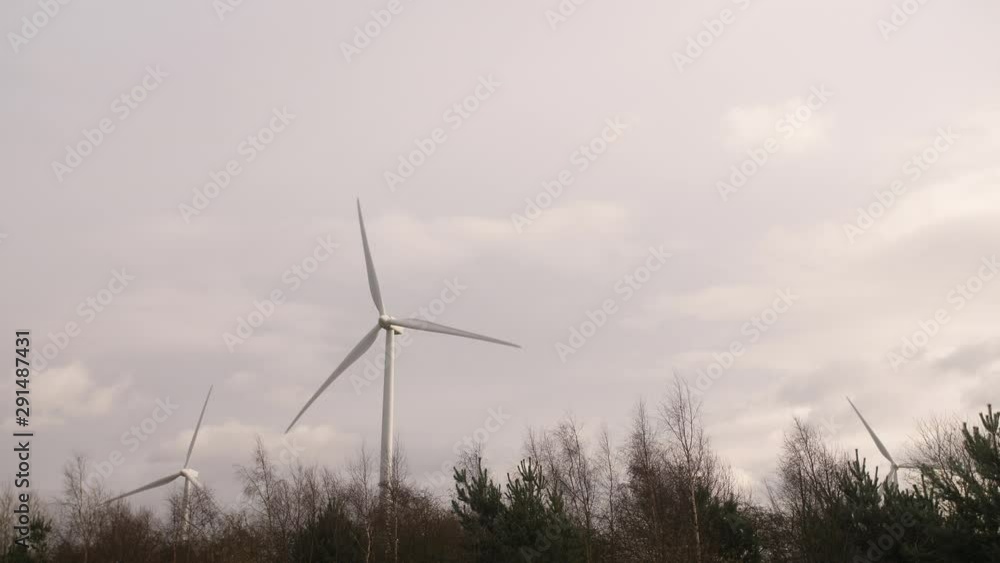 Renewable energy wind turbine spinning blades on a cloudy day by the road Renewable energy wind turbine spinning blades on a cloudy day by the road