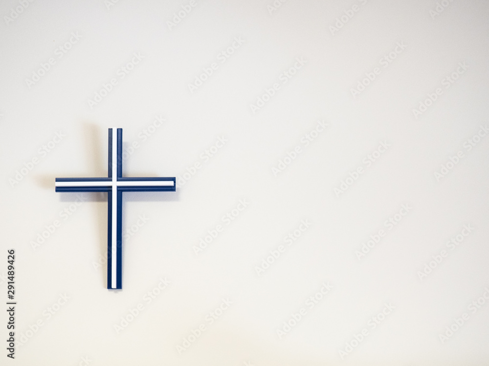 Blue and white catholic cross on a wall with copy space