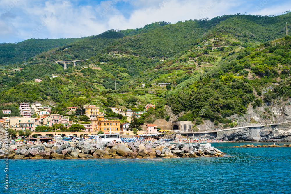 Monterosso al Mare, Cinque Terre, Italy - August 17, 2019: Boats on the pier, houses on the hill, city view / City beach on the sea coast