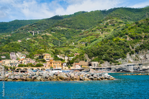 Monterosso al Mare, Cinque Terre, Italy - August 17, 2019: Boats on the pier, houses on the hill, city view / City beach on the sea coast