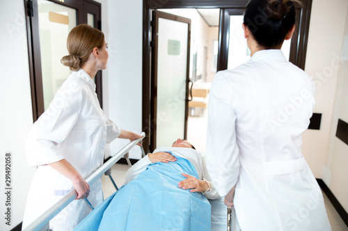 Two nurses transporting patient in clinic stock photo