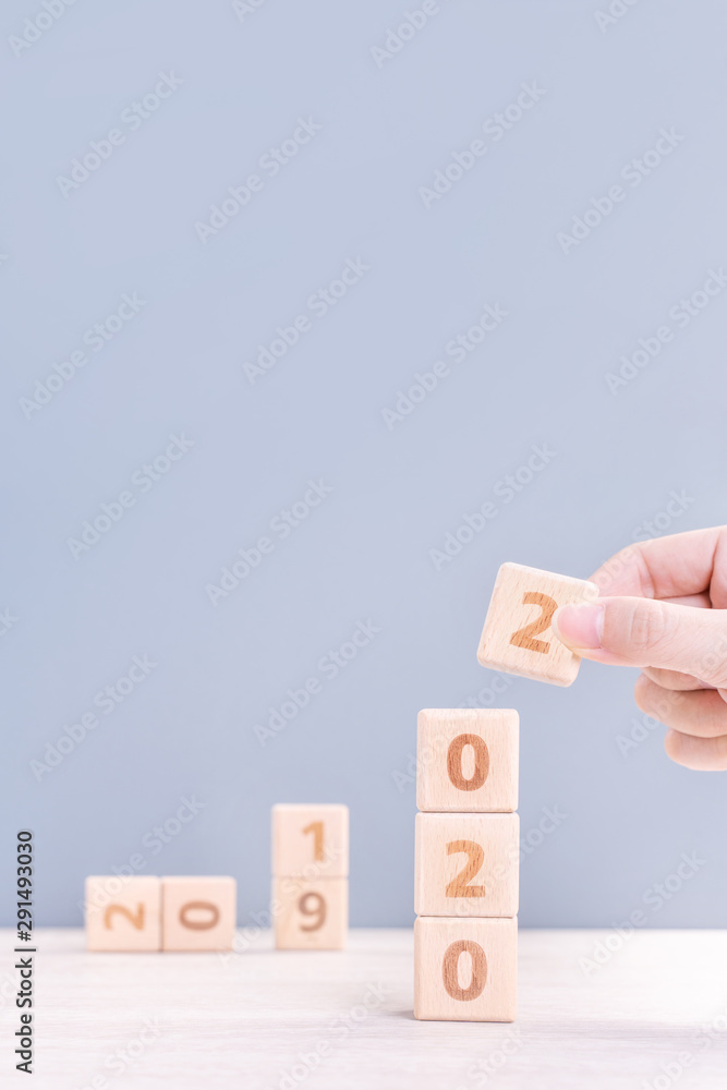 Abstract 2020 & 2019 New year countdown design concept - woman holding wood blocks cubes on wooden table and blue background, close up, copy space. Abstract 2020 & 2019 New year countdown design concept - woman holding wood blocks cubes on wooden table and blue background, close up, copy space.
