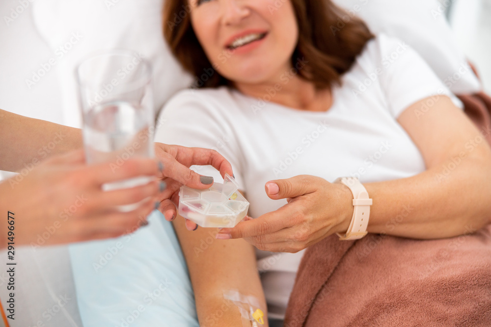 Smiling female patient is taking pills in clinic
