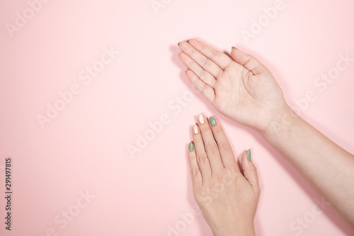 Closeup top view of two female hands laying on pink background. Horizontal color photography.