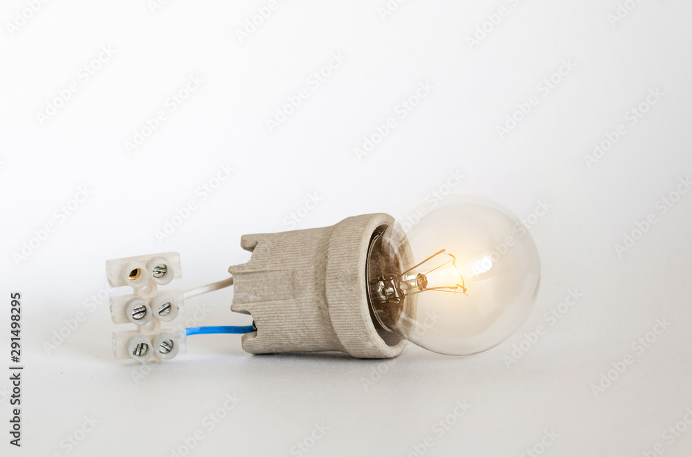 Lighting incandescent lamp bulb with cap, socket, wires and terminal block lies on white background, new idea concept