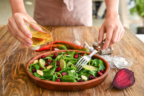 Woman preparing tasty salad at table, closeup