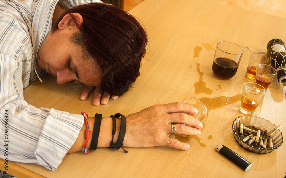 drunk depressed girl leaning against the table with glasses still full drunk depressed girl leaning against the table with glasses still full